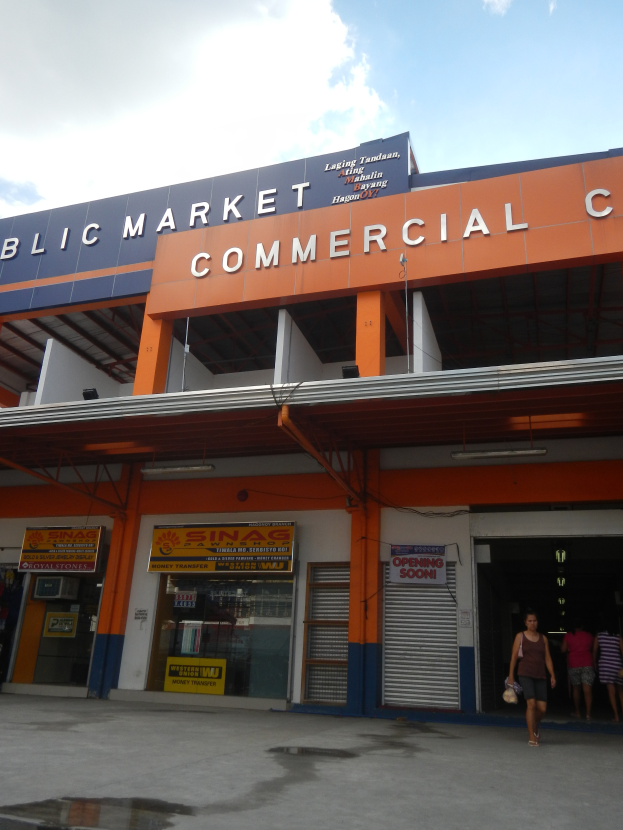 Ein öffentlicher Markt mit Menschen davor, mit Text auf dem Gebäude und einem sichtbaren Himmel oben.