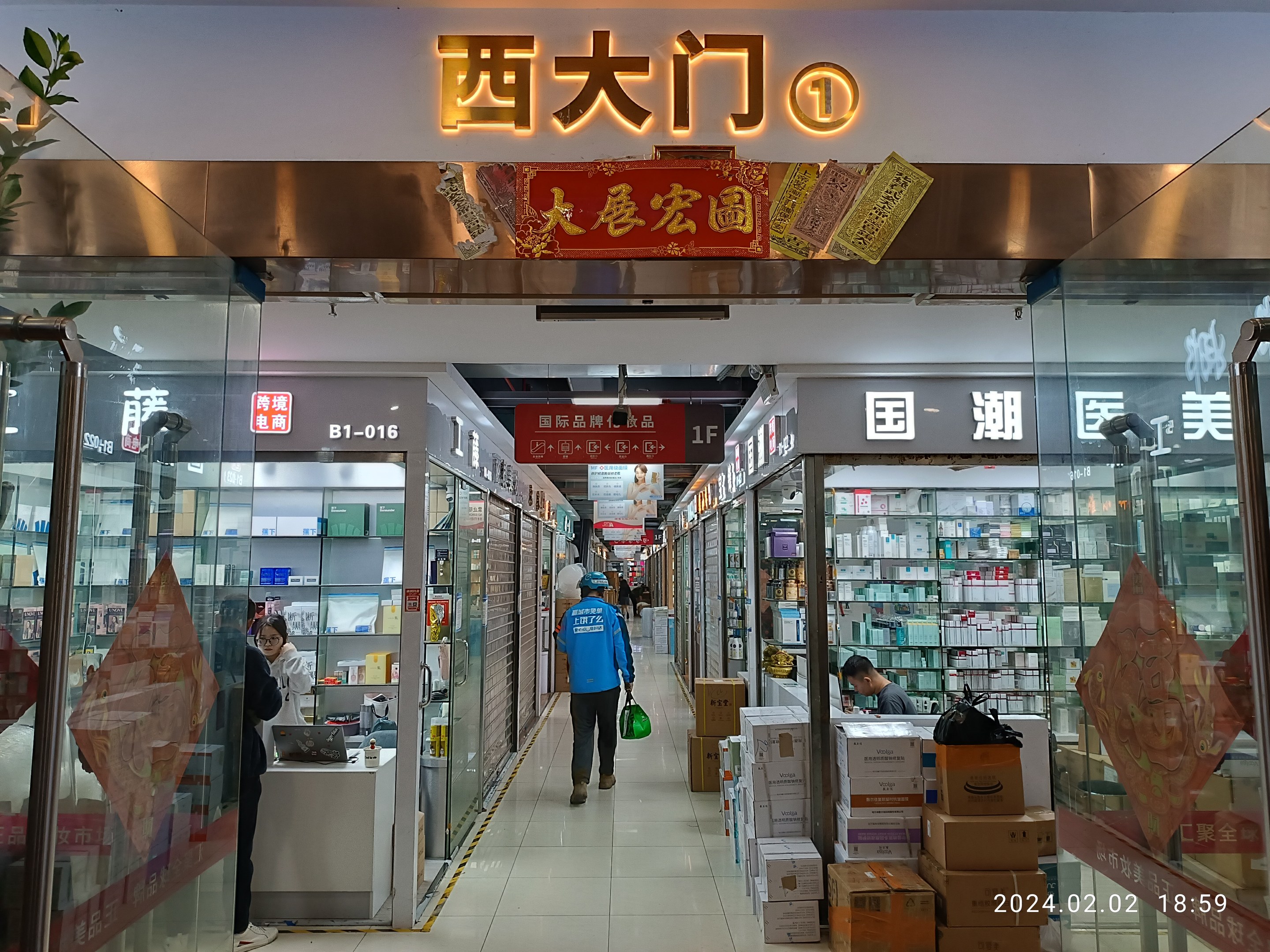 Innenraum einer chinesischen Apotheke mit Glaswänden, Regalen, verstreuten Kartons und einer Pflanze auf der linken Seite; ein Schild oben zeigt an, dass es sich um eine chinesische Drogerie handelt.