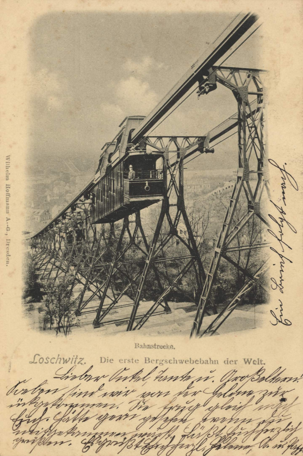 Ein altes Schwarz-Weiß-Foto einer Eisenbahnbrücke mit einem Kran, umgeben von Bäumen und einem bewölkten Himmel, mit dem Text "Bahnstrecka, die erste Eisenbahnbrücke Deutschlands" unten.