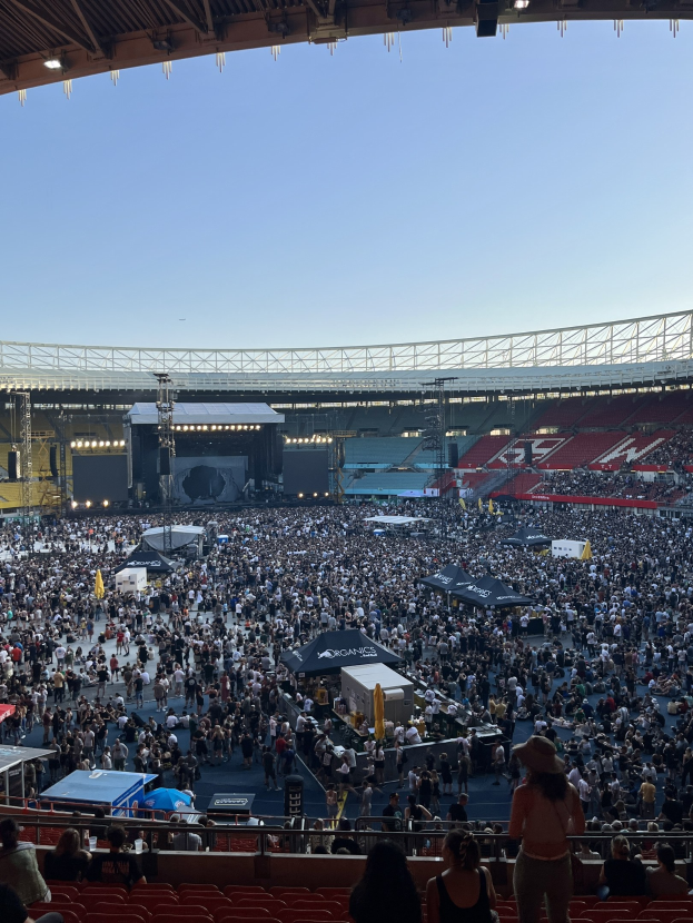 Große Menschenmenge in einem Stadion mit Zelten, Geländern und Überdachungsleuchten während eines Konzerts in der O2 Arena in London.