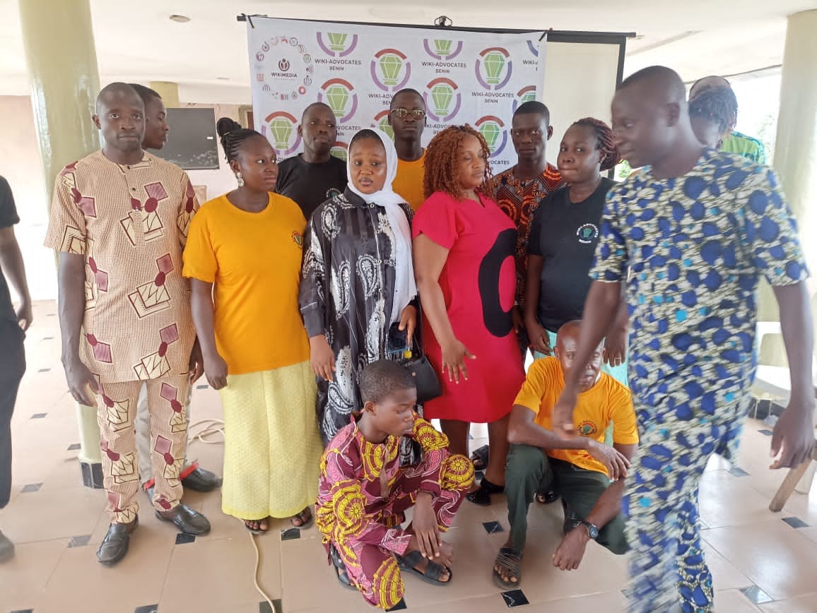 Eine Gruppe von Menschen vor einem Banner mit der Aufschrift "Advocates in Ghana: Ein Schritt-für-Schritt-Führer", umgeben von Stühlen, Säulen, einem Fernseher und einer Decke mit Deckenleuchten.