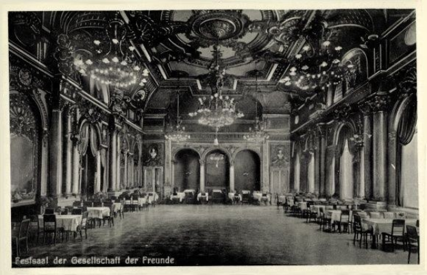 Schwarz-weiß-Foto eines großen Raums mit Tischen, Stühlen, Säulen, Bögen und Deckenleuchter; Text unten lautet "Festival der Gesellschaft der Freunde, Berlin".