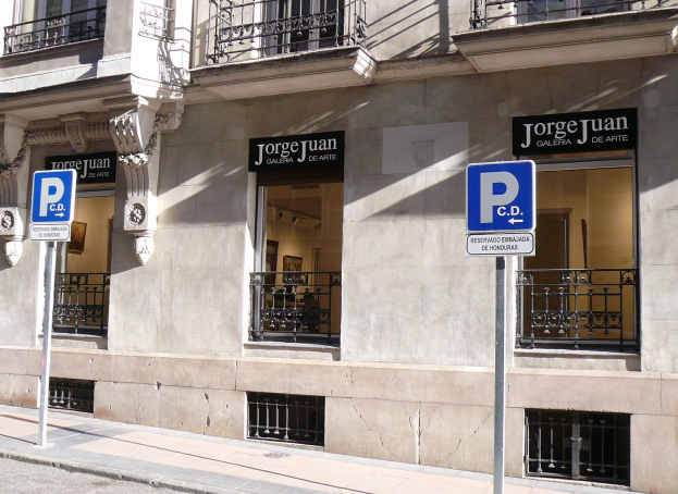 Ein mehrgeschossiges Gebäude mit Fenstern, Geländern, Türen und Säulen, das Werbetafeln an Pfosten entlang des Gehwegs und sichtbare Innenobjekte aufweist, die auf eine belebte städtische Umgebung hinweisen.