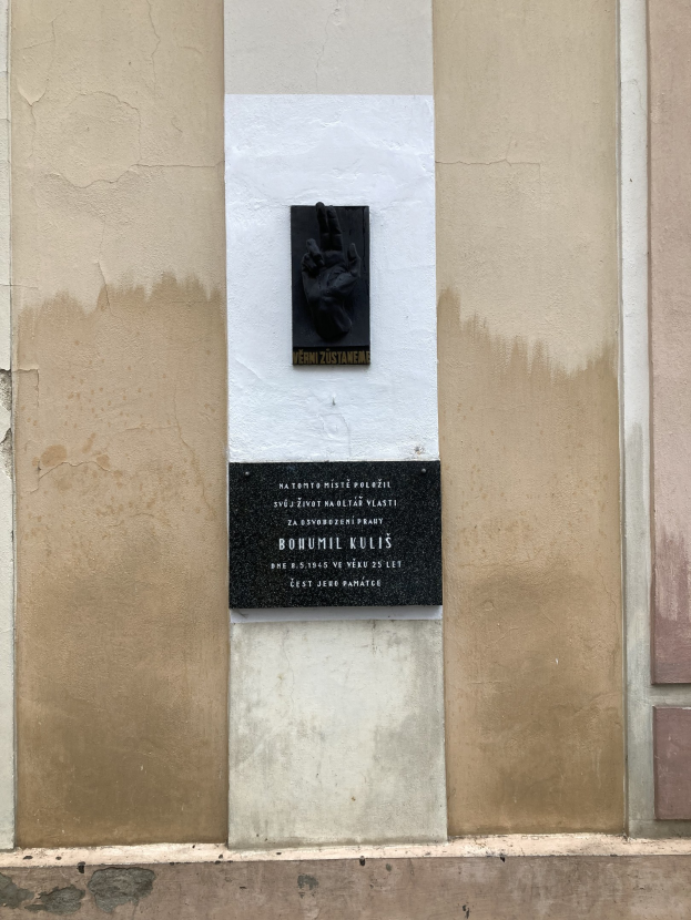 Schwarze Plakette an einem Gebäude mit einer Hand darauf, die einen Text zeigt, der Holocaust-Opfern gedenkt.