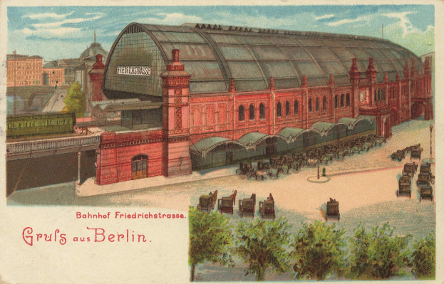 Alte Postkarte, die einen Bahnhof in Berlin, Deutschland, mit einem Gebäude, Bäumen, Karren, Menschen, einer Brücke und einem bewölkten Himmel zeigt, einschließlich Text am unteren Rand.