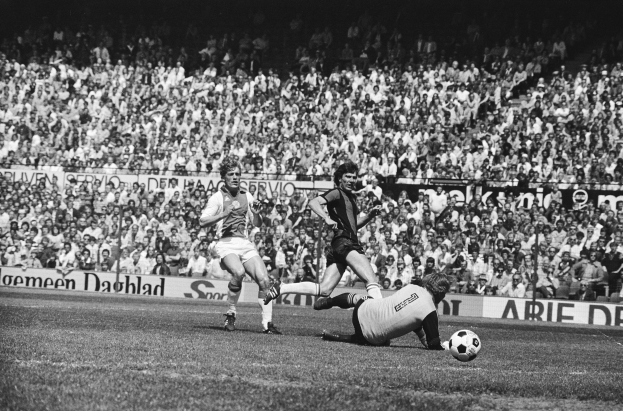 Schwarzes Foto von Fußballspielern im Einsatz auf einem Feld mit Zuschauern im Hintergrund und einer Bundesliga 1978-79 Ajax 1-1 Hannover 96 Fahne.