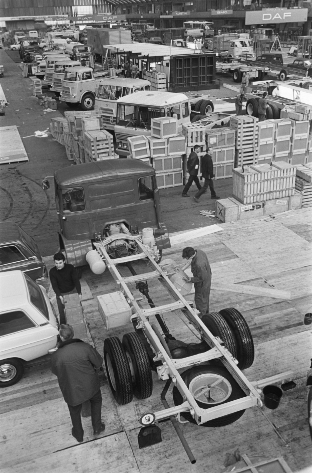 Schwarzes und weißes Foto von Männern, die an einem Truck in einer Fabrik arbeiten.