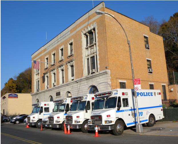 Polizeifahrzeuge vor einem Gebäude mit einer Tafel, einer Flagge und Verkehrskegeln geparkt.