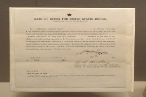 Ein Blatt Papier mit dem Text "Eid für Bundesrichter" liegt auf einem Tisch vor einer Wand.