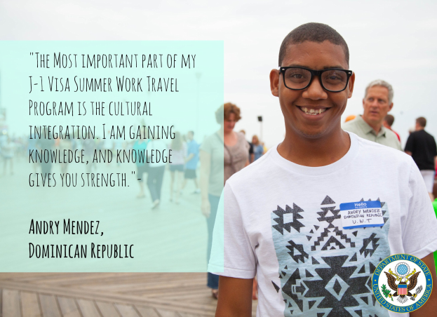 Ein Mensch in einem weißen T-Shirt lächelt, während er zwischen einer Gruppe auf einer hölzernen Oberfläche geht, mit einem Zitat über kulturelle Integration von Andry Mendez auf der linken Seite, vor Buildings und einem klaren blauen Himmel.