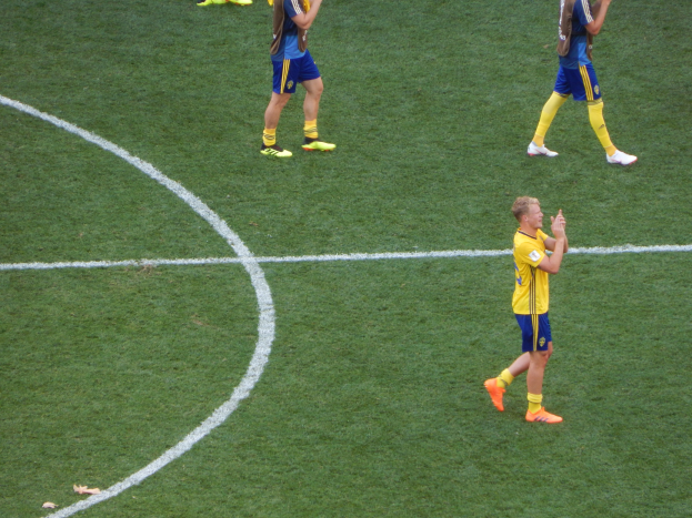 Gruppe von Männern in Fußballtrikots klatscht feierlich auf einem Fußballfeld.