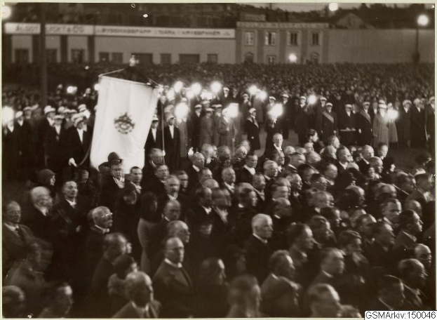 Schwarzes und weißes Foto einer großen Menge vor einem Gebäude, mit einer Person, die eine Fahne hält, und Polen, Lichter und Text im Hintergrund, der "Gustav Klimts Rede an der Berliner Mauer" lautet.