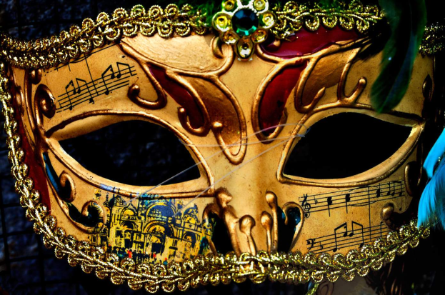 Ein Nahaufnahme eines Faschingsmasken mit detaillierten Designs, Federn und Noten, mit einem unscharfen Hintergrund.