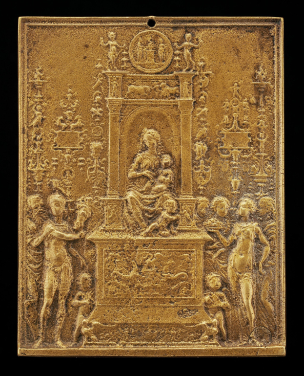 Eine goldene Plakette mit einer detaillierten Skulptur einer Frau in einem langen Kleid und eines Mannes in einem Anzug und Krawatte, eingerahmt von einem prunkvollen goldenen Rahmen, vor einem schwarzen Hintergrund.