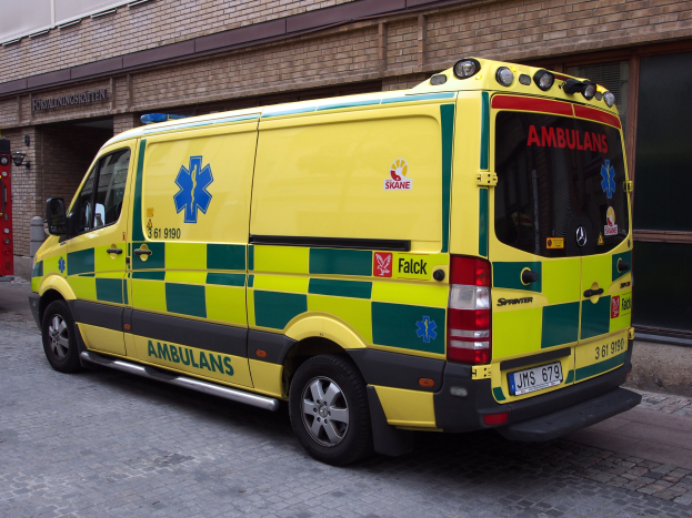 Ambulanz auf der Straße vor einem Ziegelgebäude mit Text geparkt, mit einem Feuerlöscher auf der linken Seite sichtbar.