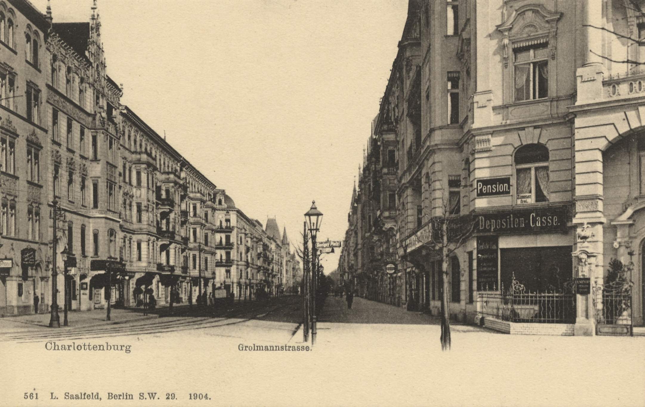 Altes Schwarz-Weiß-Foto einer Stadtstraße in Charlottenburg, Deutschland, mit Gebäuden, Straßenlaternen, Lampen, Namensschildern, Kraftfahrzeugen, Fußgängern, Gittern und einem klaren Himmel.