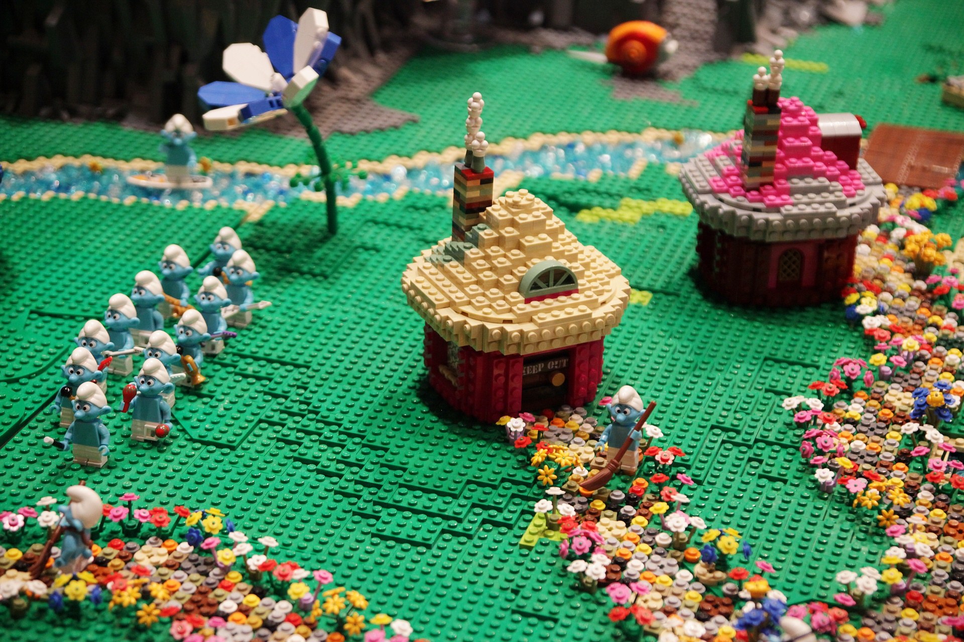 Ein Lego-Modell einer Kleinstadt mit Blumen, Spielzeugen, Häusern, Pflanzen und anderen Gegenständen vor einem leicht unscharfen, träumerischen Hintergrund.
