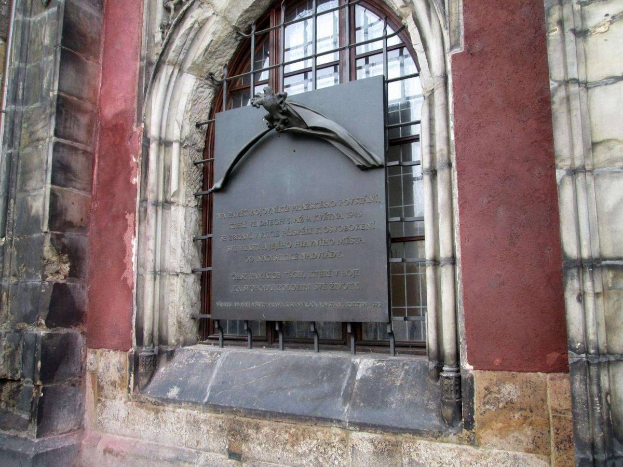 Steinernes Gebäude mit einem Fenster und einer Holocaust-Gedenktafel mit Inschrift.