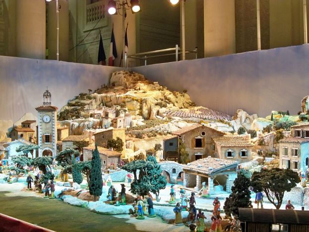 Ein detailliertes Miniatur-Krippen-Szenario in einem Museum, mit Figuren, Strukturen und Beleuchtungselementen unter Museumsbeleuchtung.