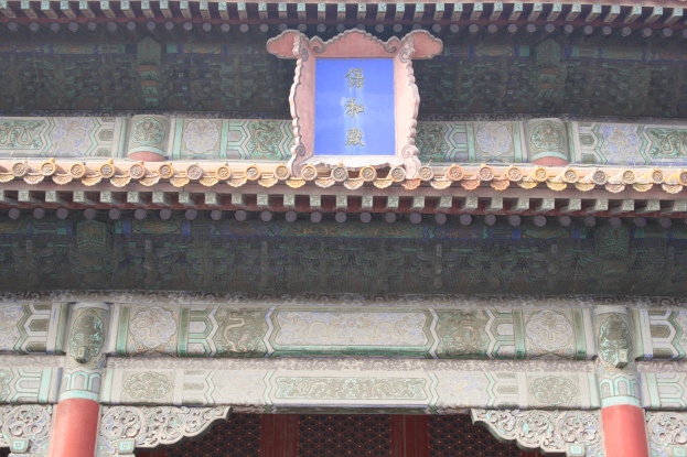 Der Eingang zur Verbotenen Stadt in Peking, China, mit einem Gebäude mit detaillierten Entwürfen, Säulen und einer Tafel mit Text.