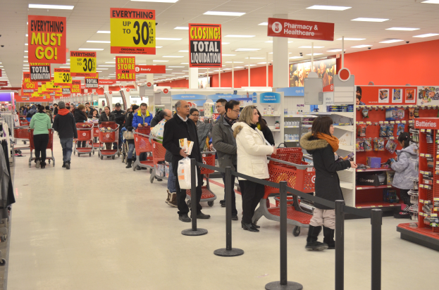 Ein volles Walmart-Geschäft mit Einkaufswagen schiebenden Kunden, umgeben von Warenpräsentationen, Schildern und Deckenleuchten.