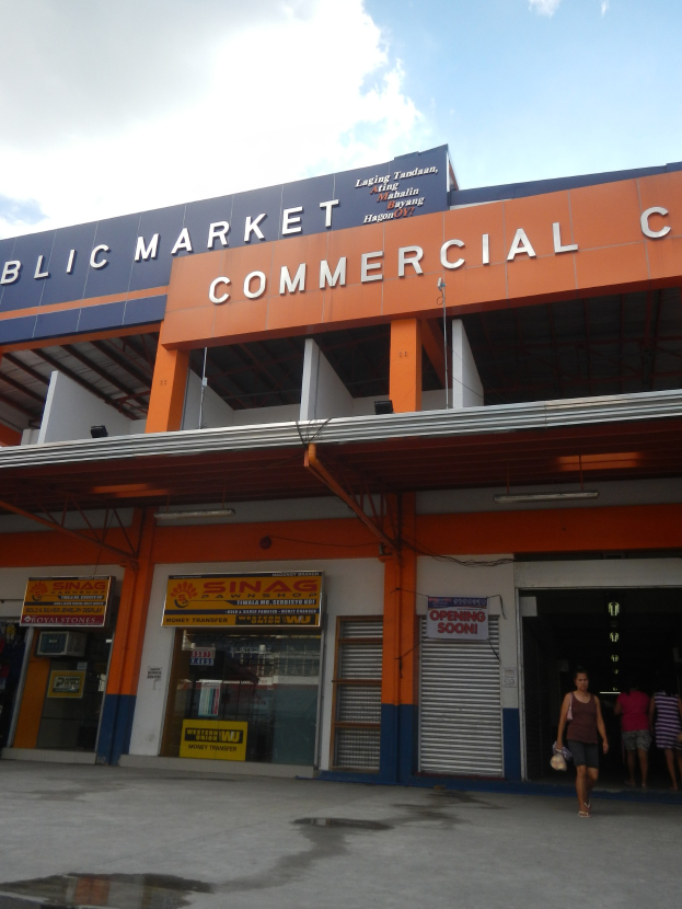 Öffentliches Marktzentrum mit Menschen vor dem Gebäude, Text auf dem Gebäude und Himmel darüber.